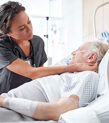 Nurse adjusts nasal cannula on elderly male patient for continuous respiratory monitoring