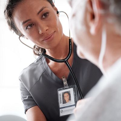 A nurse uses a stethoscope to assess her patient in a hospital setting