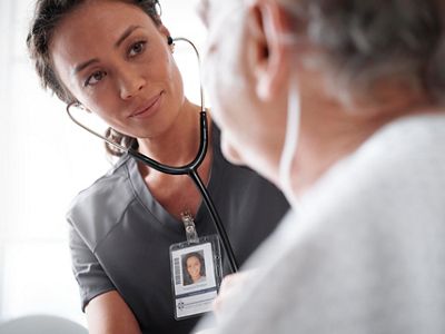 A nurse using stethoscope on patient sitting in Centrella® Smart+ bed