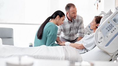 A patient is comforted by family members in a Hillrom™ Centrella® Smart+ Bed. 