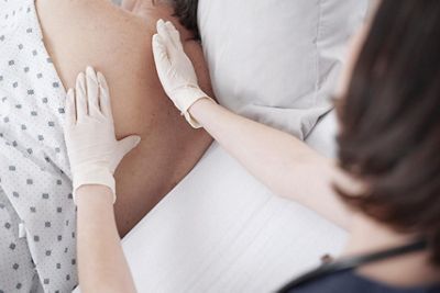 A nurse checks for signs of pressure injuries on a patient’s back