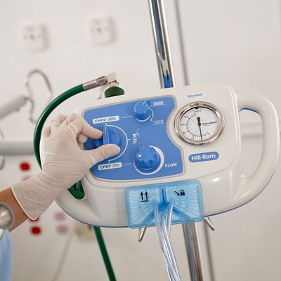 A clinician with a gloved hand adjusts a control knob on the MetaNeb System Controller