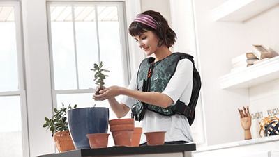 A young woman wears her Monarch vest while potting plants in her home