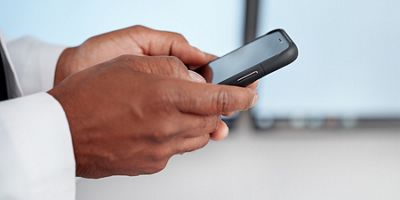 Close-up of doctor using mobile device in hospital hallway
