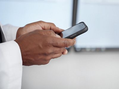 Close-up of doctor using mobile device in hospital hallway