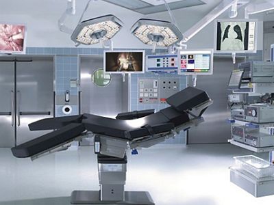 A modern operating room with surgical table, monitors, overhead lights and other equipment