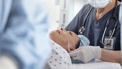 An anesthesiologist places a nasal cannula on a patient before surgery