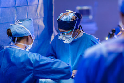 Two surgical team members perform surgery in the  operating room