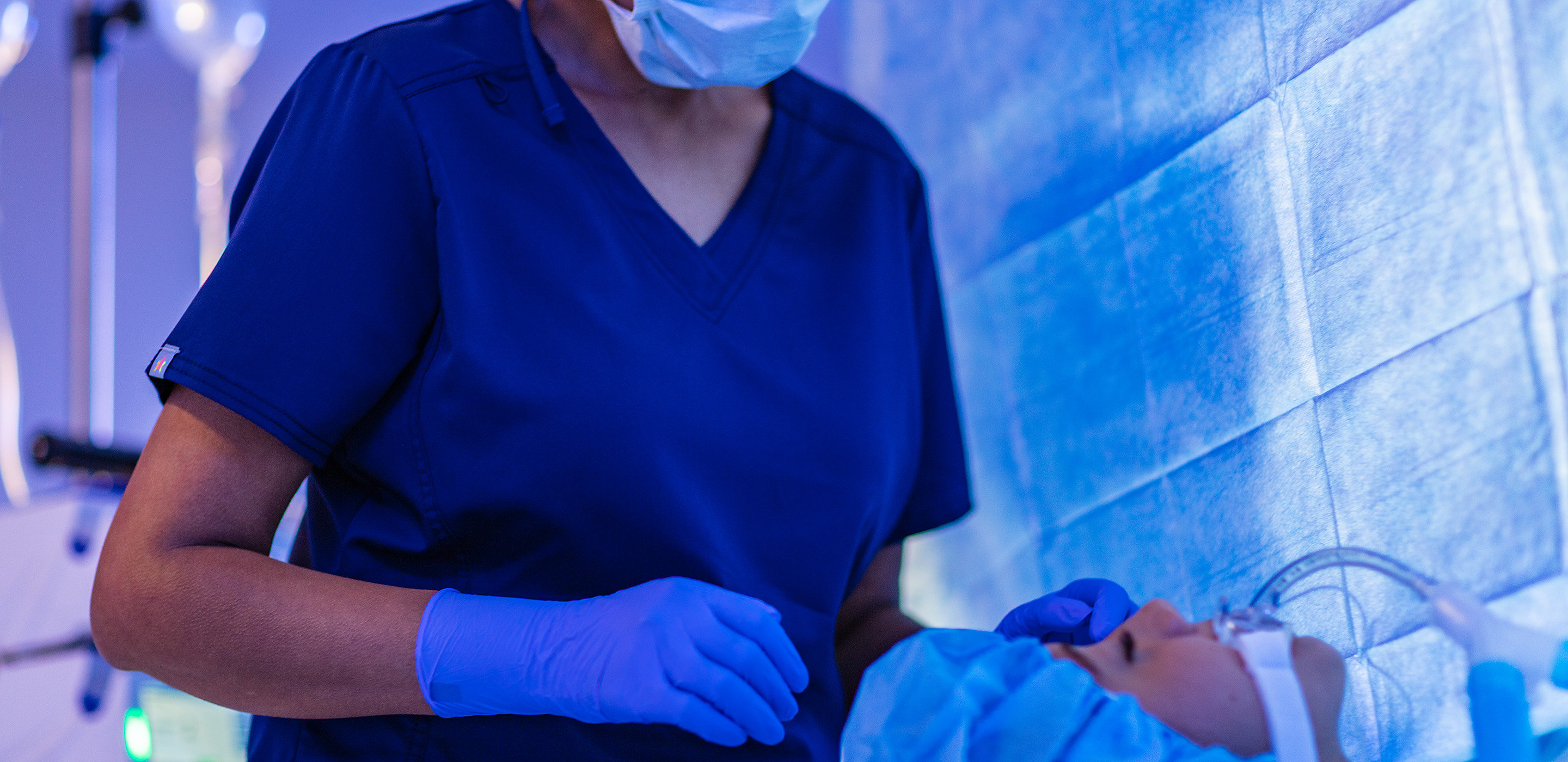 A surgical clinician watches over her patient during surgery
