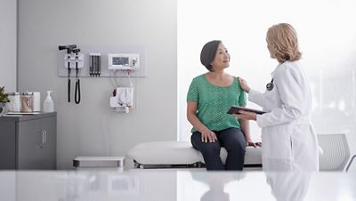 A physician speaks to a female patient in an exam room.