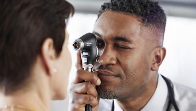 A physician looks into a patient’s eye with the PanOptic Plus Ophthalmoscope.