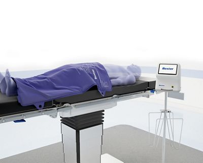 Surgical patient is pictured with warming blanket and heated table pads next to controller unit