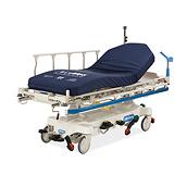Hillroms procedurakutvagn, diagonal vy med Accumax Quantum™-madrass och blått stötskydd.