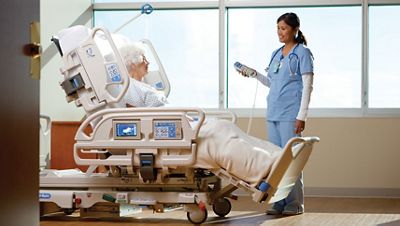 A clinician operates a Progressa bed system with patient seated within