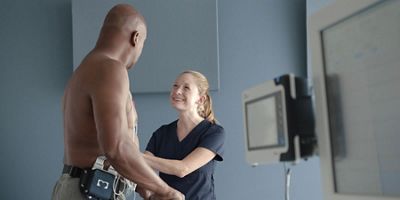 A clinician speaks with a patient on a treadmill before a cardiac stress exam.