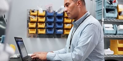 A biomedical engineering manager sits at their workstation and uses Hillrom’s remote device management solution, SmartCare Remote Management, on his laptop. 