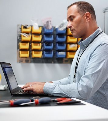 A biomedical engineering manager sits at their workstation and uses Hillrom’s remote device management solution, SmartCare Remote Management, on his laptop. 