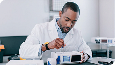 Healthcare professional in a lab adjusts a medical infusion pump device using a screwdriver.