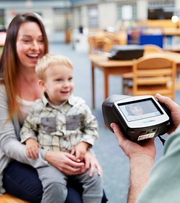 A child receives a vision screening from a Welch Allyn® Spot® Vision Screener.