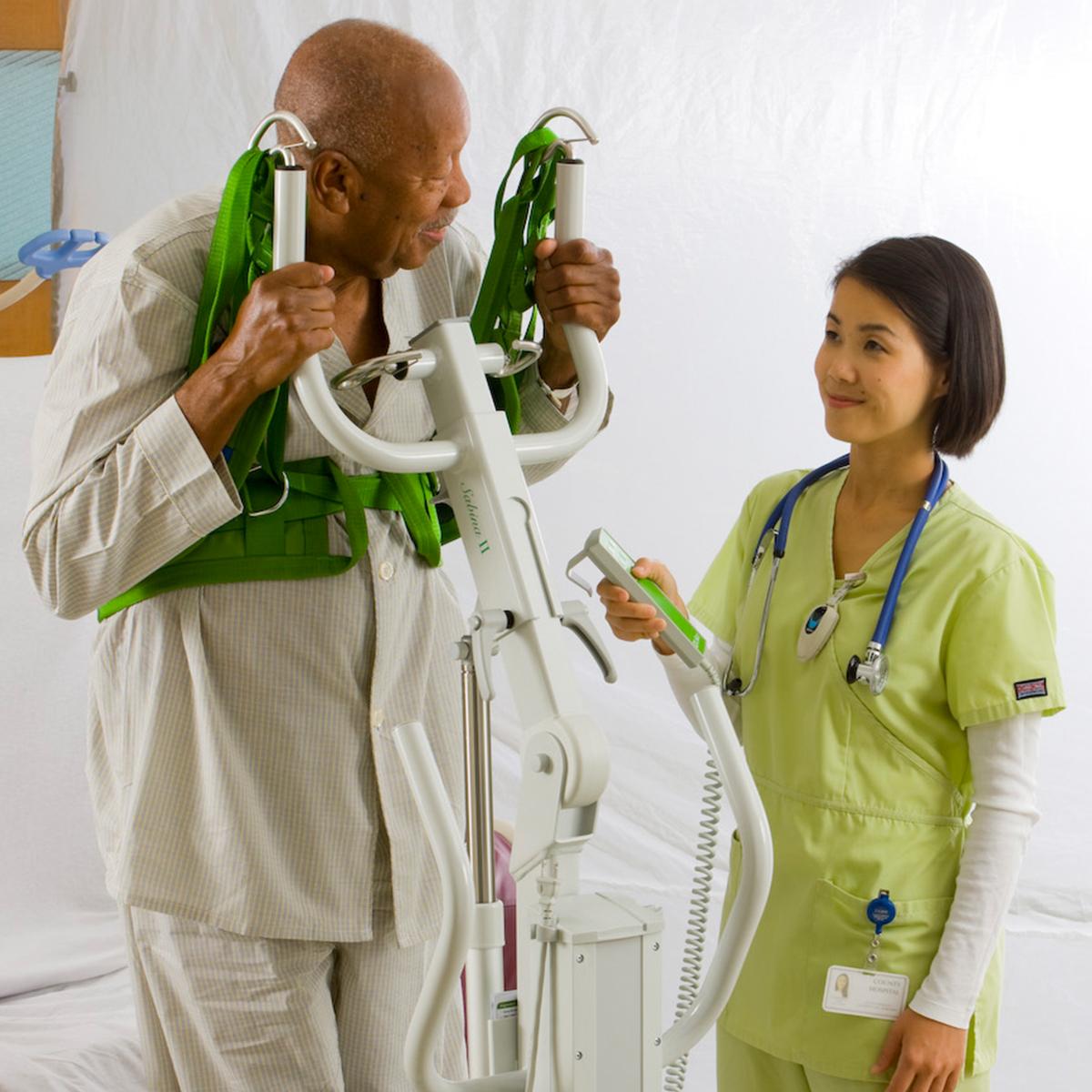 A clinician helps an older male patient stand using a Sabina SafetyVest Lift Aid