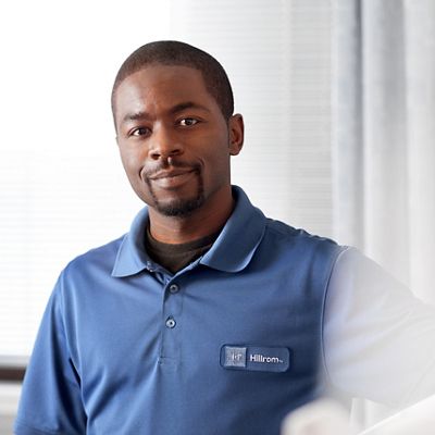 A Hillrom representative smiles confidently from a hospital bedside