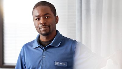 A Hillrom representative smiles confidently from a hospital bedside