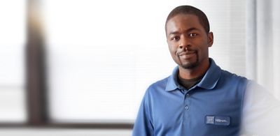 Un technicien Hillrom debout à côté d’un lit d’hôpital sourit avec confiance à la caméra.