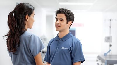 A nurse speaking with a Hillrom™ Care Communications Service Professional in hospital hallway