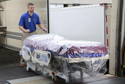 A Baxter employee smiles while delivering a Progressa rental ICU bed