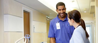 A Hillrom service representative talks with a clinician about the Progressa Bed System in a hospital hallway