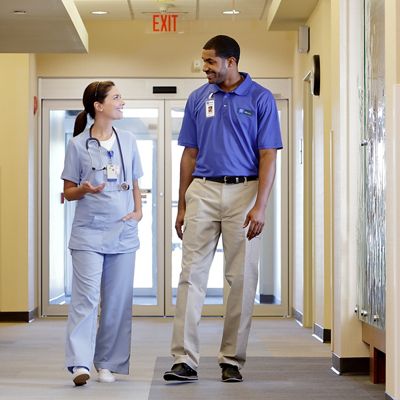 Nurse and Hillrom technician interacting in a hospital hallway