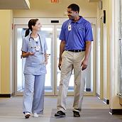 Infirmière et technicien de Hillrom discutant dans un couloir d'hôpital