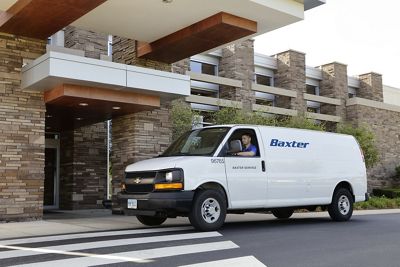 A smiling Hillrom service technician drives a Hillrom service vehicle