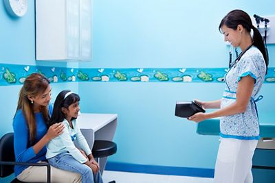 Physician screening child and parent in office with Spot Vision Screener