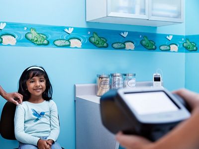 Primary care physician using Spot Vision Screener on young child