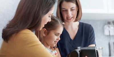 Clinician shows vision screening results to child and mother.
