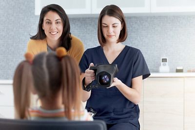 A child sits on his mother’s lap while having his vision screened with the Spot Vision Screener 