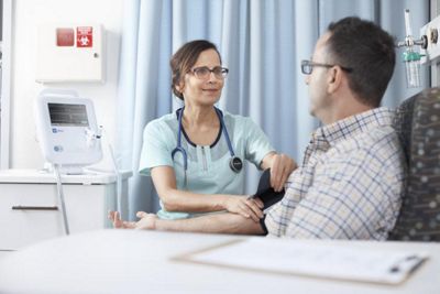 healthcare professional holding patients arm with blood pressure cuff