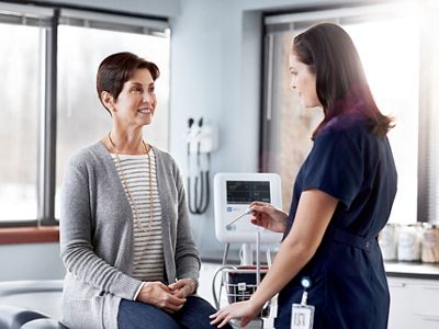 Un clinicien se prépare à prendre la température d'un patient à l'aide d'un dispositif de paramètres vitaux Spot 4400