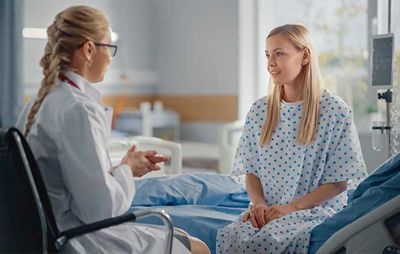 Medical professional with a femal patient talking in a hospital room