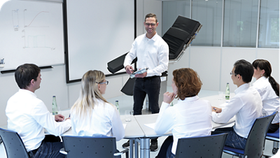 Healthcare educator leading a training session for clinicians using a whiteboard in a classroom setting.