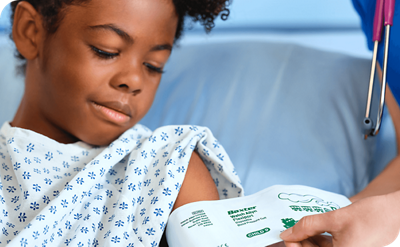 child laying in hospital bed with nurse adjusting blood pressure cuff