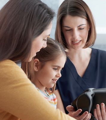 Mother and clinician with a child looking at a Welch Allyn® Spot® Vision Screener.