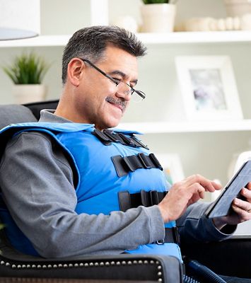 A man taps a tablet screen while using The Vest System.