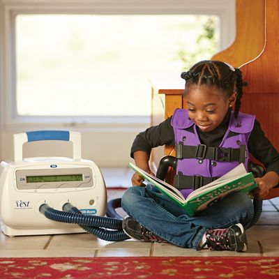 Sistema The&nbsp;Vest, modelo&nbsp;105, una niña pequeña que viste un chaleco color morado está leyendo un libro mientras recibe tratamiento