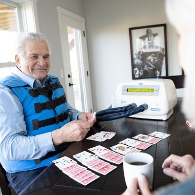 Een oudere man gebruikt het The Vest-systeem terwijl hij patience speelt aan zijn eettafel.