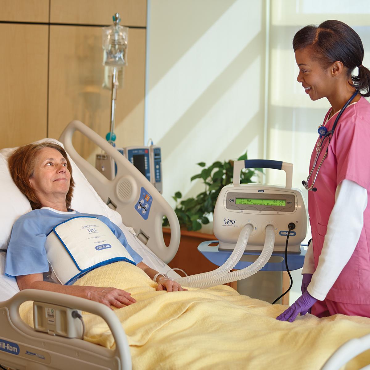 Eine Patientin in einem Krankenhausbett erhält eine Behandlung mit der The Vest System, Modell 205 Wickelweste.