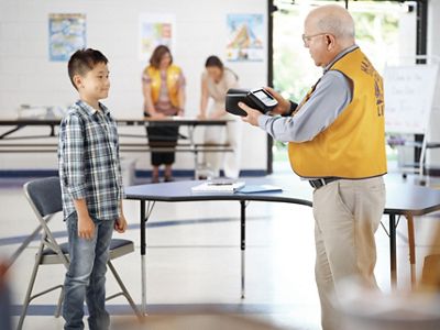 School-age boy getting vision screened by Lions Club member
