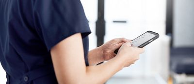 A clinician reads information on her phone in a hospital setting