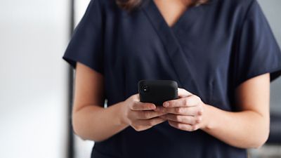 Clinician looks at a cell phone that is displaying information or alerts